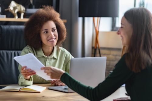 Healthcare professional sitting at a desk reviewing documents with a client