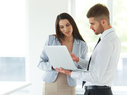 Woman in blue blazer and man in white shirt and tie looking at a tablet